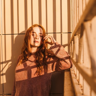 Eine Frau steht auf einer Veranda in der Sonne.