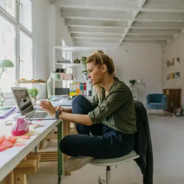 Multitasking: Frau sitzt an einem Schreibtisch am Laptop.