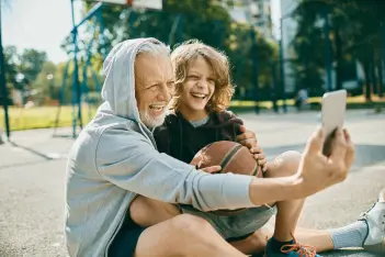 Starke Knochen im Alter: Großvater und Enkelkind in Sportoutfits machen ein Selfie.