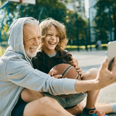 Starke Knochen im Alter: Großvater und Enkelkind in Sportoutfits machen ein Selfie.