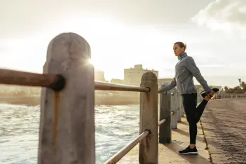 Dehnen hilft bei Wadenkrämpfen: Frau in Sportkleidung dehnt ihr Bein.
