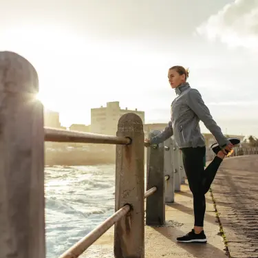 Dehnen hilft bei Wadenkrämpfen: Frau in Sportkleidung dehnt ihr Bein.