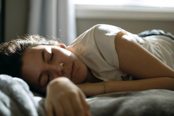 Junge Frau liegt schlafend auf einem Bett