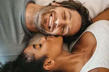 Ein Paar liegt Kopf an Kopf im Bett