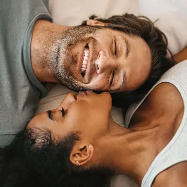 Ein Paar liegt Kopf an Kopf im Bett