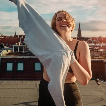 Frau in Sportoutfit zieht Pullover über