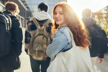 Schülerin mit Umhängetasche schaut in die Kamera