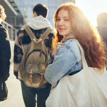 Schülerin mit Umhängetasche schaut in die Kamera
