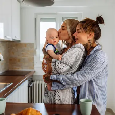 Gemeinsam gegen Mental Load: Frau umarm andere Frau mit Baby auch dem Arm