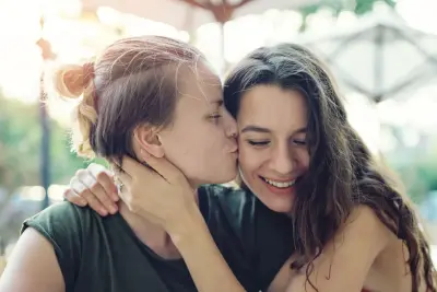 Zwei Frauen küssen und umarmen sich.