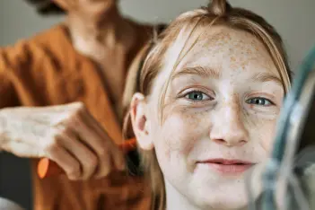 Frau frisiert Mädchen mit Sommersprossen