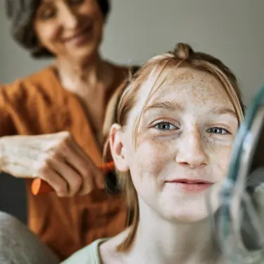 Frau frisiert Mädchen mit Sommersprossen
