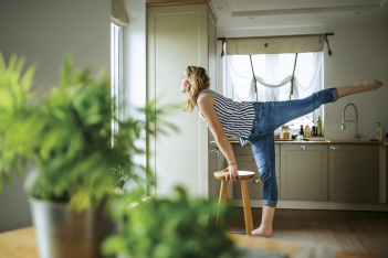 Frau im offenen Wohnbereich macht spontan Yoga auf einem Hocker
